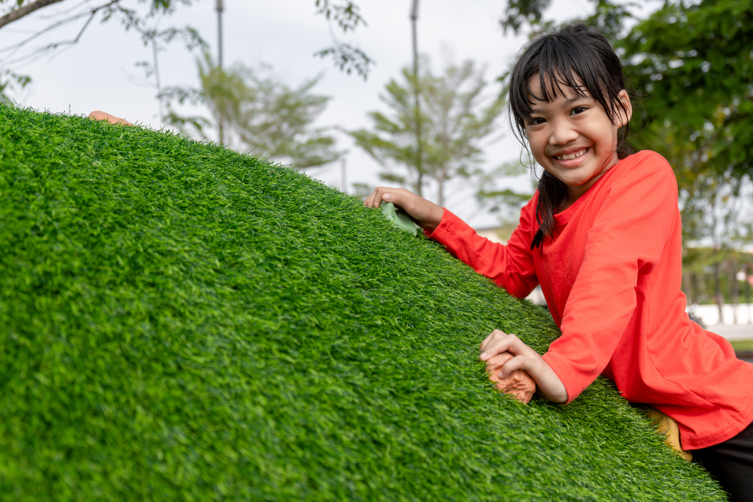child touching artificial grass on sloped surface
